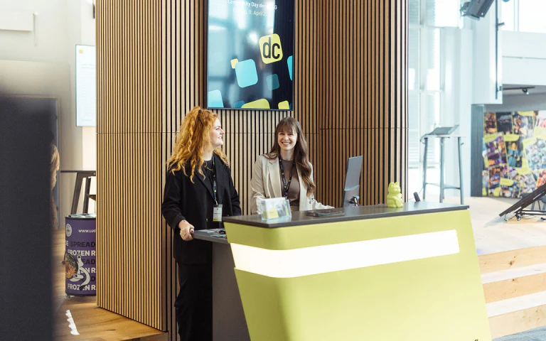 Zwei lächelnde Frauen am Empfangstresen beim dc:connect Event.