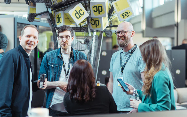 Teilnehmende unterhalten sich lächelnd auf dem dc:connect Branchen-Event.