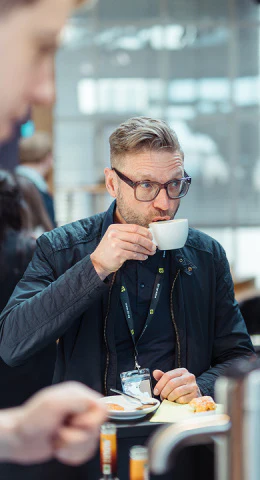 Mann mit Brille trinkt Kaffee bei einer dc:connect-Veranstaltung.