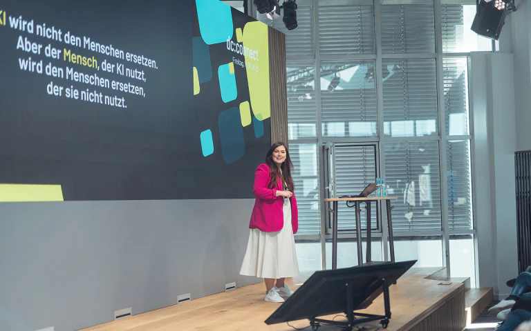 Sprecherin hält beim dc:connect Event einen Vortrag über KI auf einer Bühne.