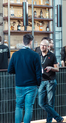 Zwei Männer unterhalten sich bei einem Networking-Event an einer Bar.