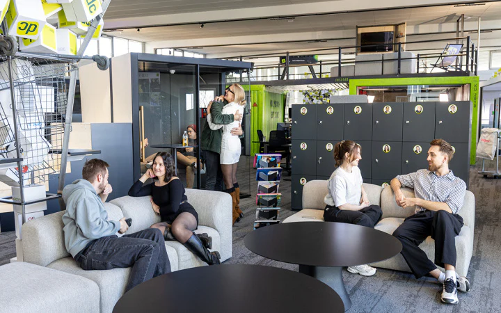 Mitarbeiter in der modernen New Work Bürolandschaft von dc beim Austausch auf Sofas.