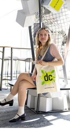 Chief Sustainability Officer Lisa Köppel hält eine Stofftasche der dc AG mit grünem Nachhaltigkeits-Logo.