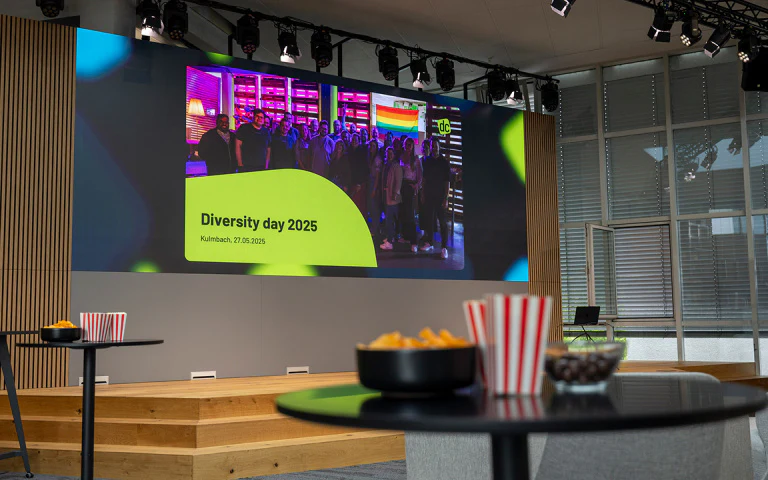 Präsentationsleinwand zeigt das dc-Team zum Diversity Day 2025 in Kulmbach mit Regenbogenflagge.