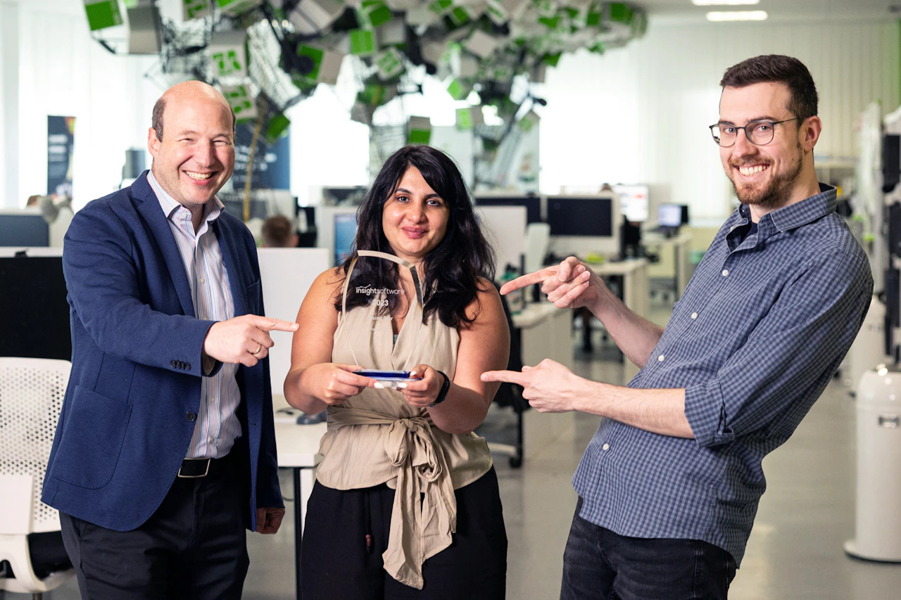 Drei lächelnde Kollegen im Büro präsentieren stolz den Rising Star Award.