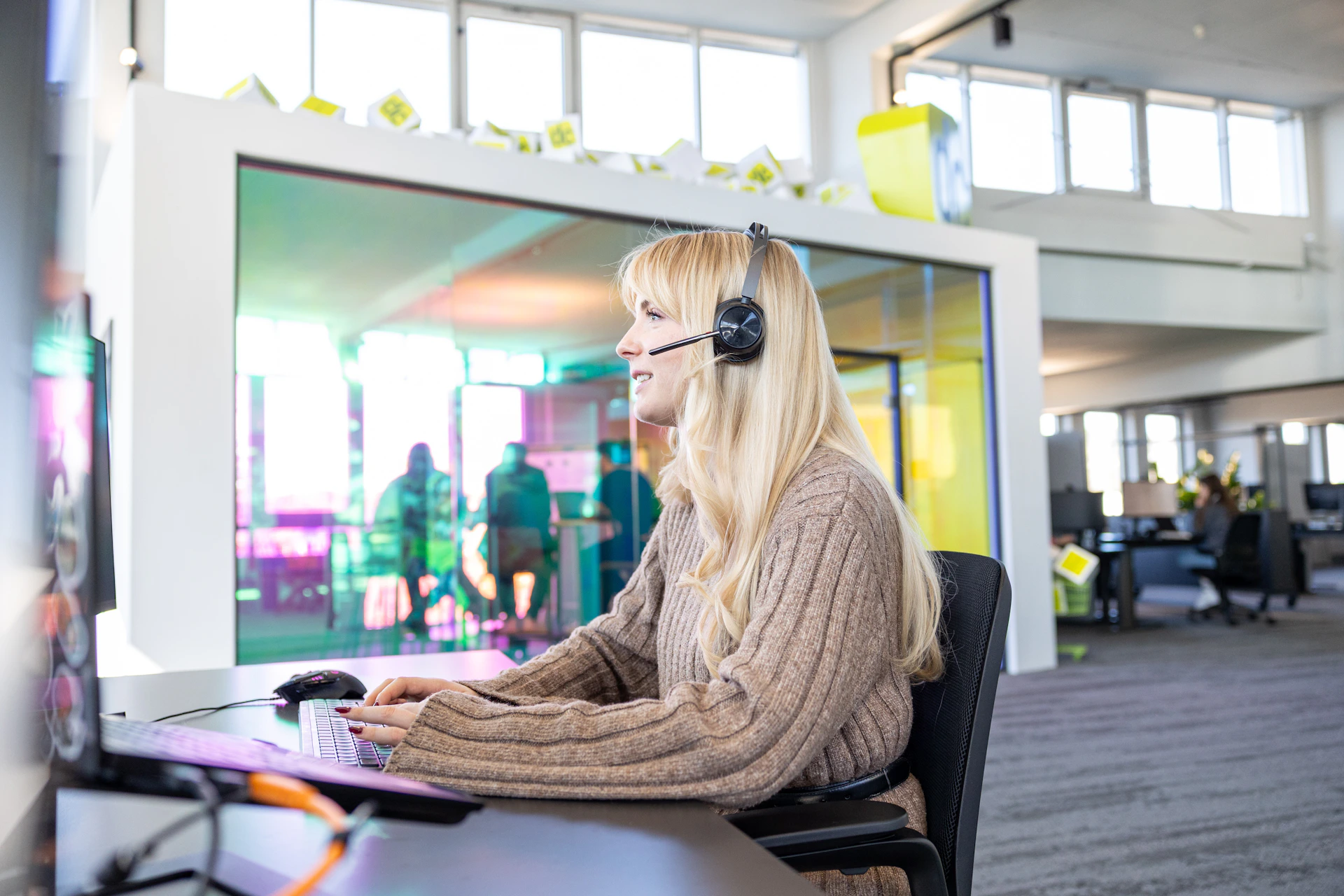 Mitarbeiterin mit Headset arbeitet an einem Computer-Arbeitsplatz im modernen Büro der dc AG.