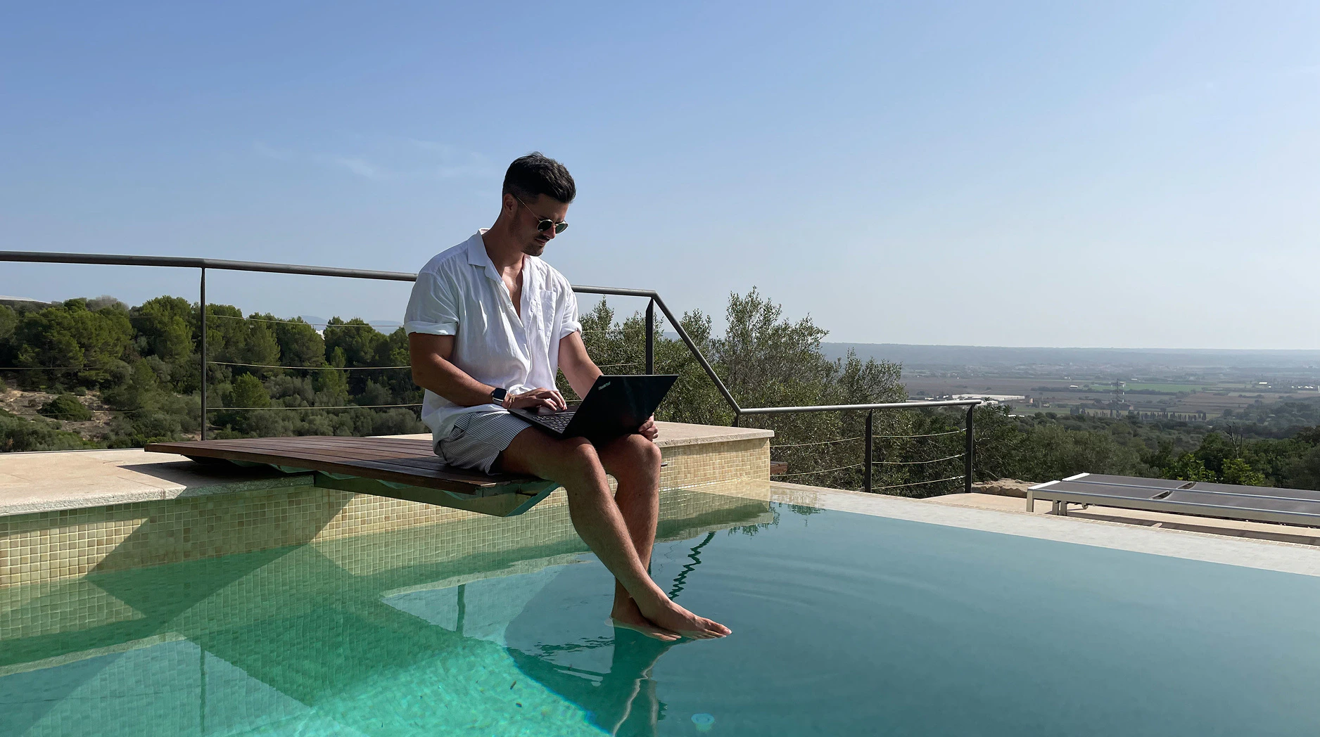 Mann arbeitet mit einem Lenovo ThinkPad Laptop am Pool unter freiem Himmel.