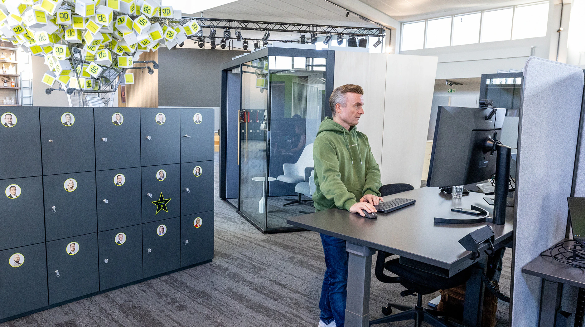 Mitarbeiter arbeitet an einem höhenverstellbaren Schreibtisch in einem modernen Open-Office-Büro.