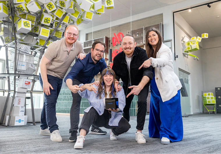 Eine Gruppe aus 5 jungen, begeisterten Personen posiert mit einem gewonnen German Web Award im Office der dc AG.