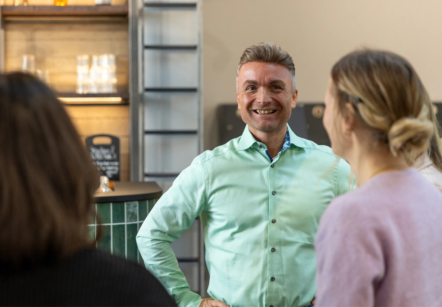 Ein lächelnder Mann im hellgrünen Hemd unterhält sich beim Online Marketing Brunch mit anderen Teilnehmern.