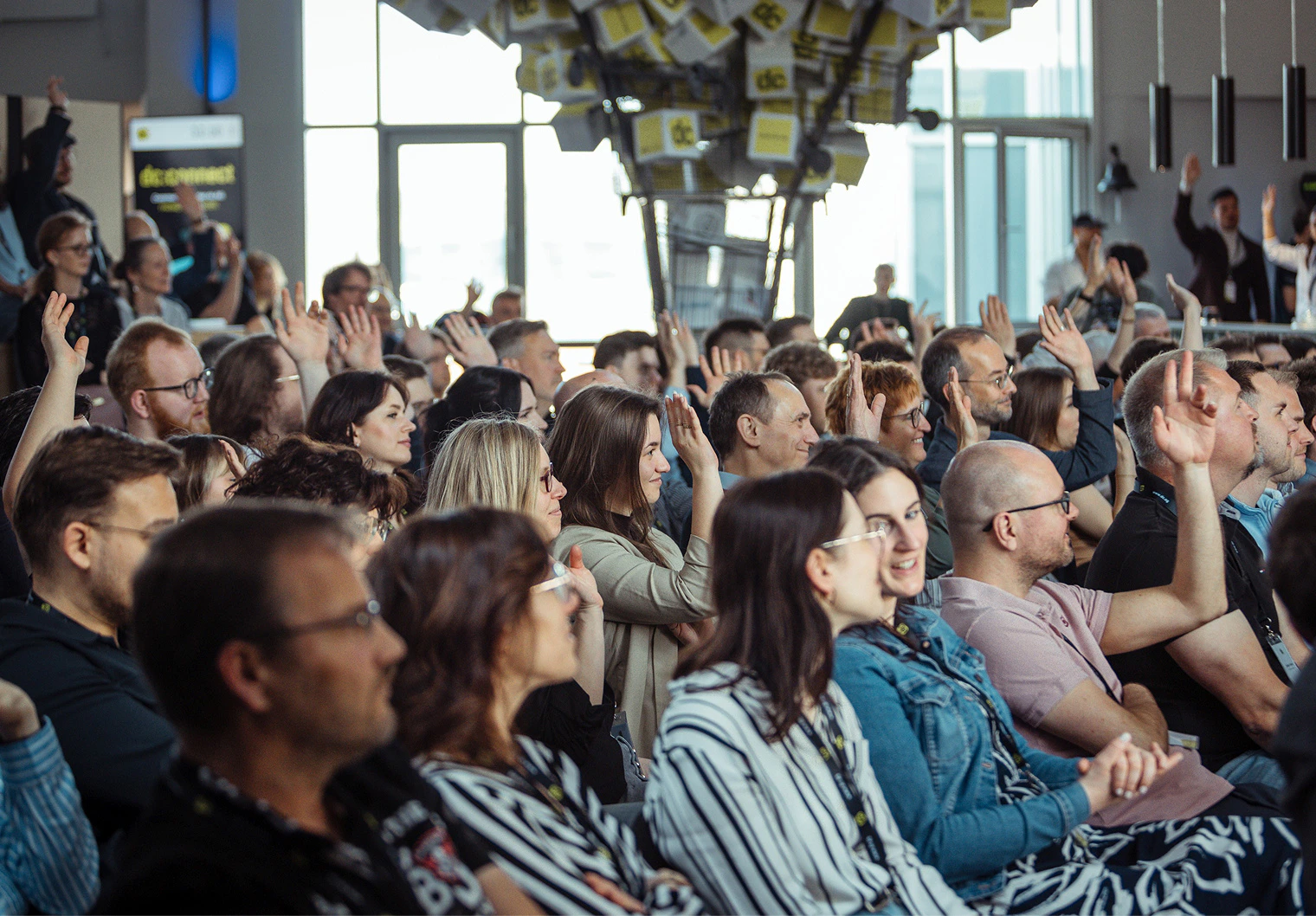 Publikum hebt bei der dc-connect Konferenz gemeinsam die Hände.