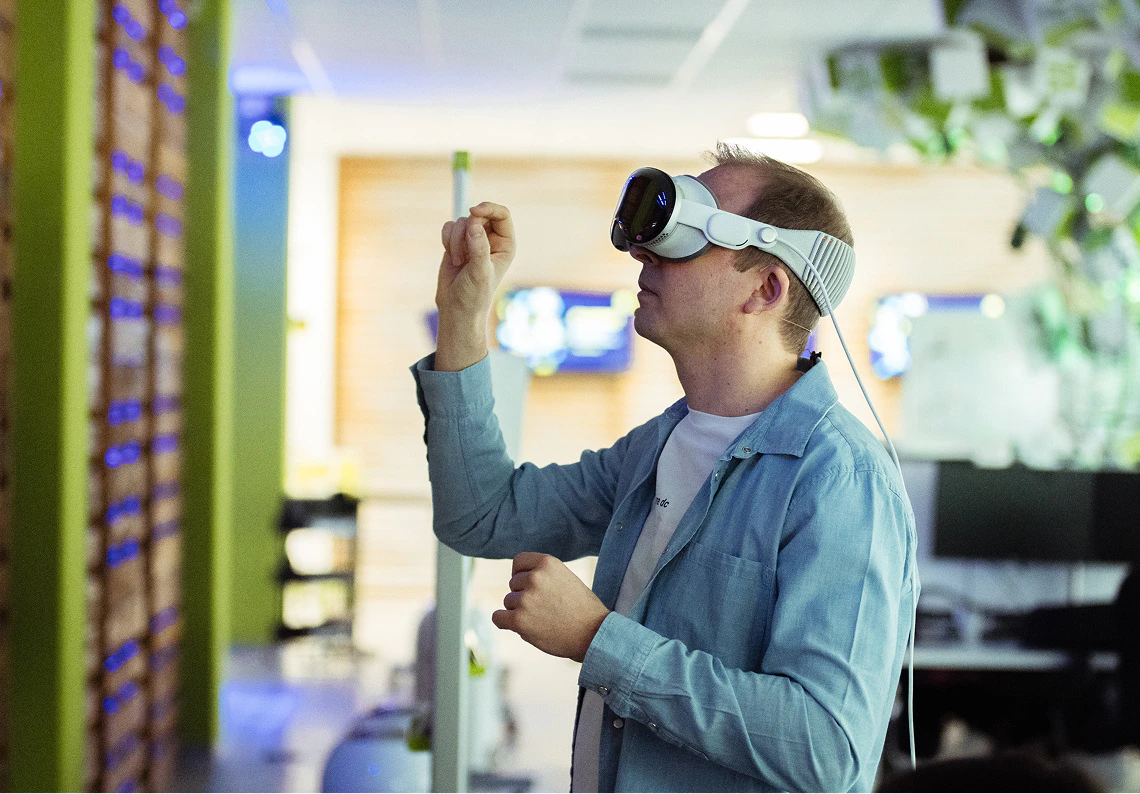 CEO Tobias Langmeyer bedient mit Gesten eine Apple Vision Pro VR-Brille im modernen dc Office.