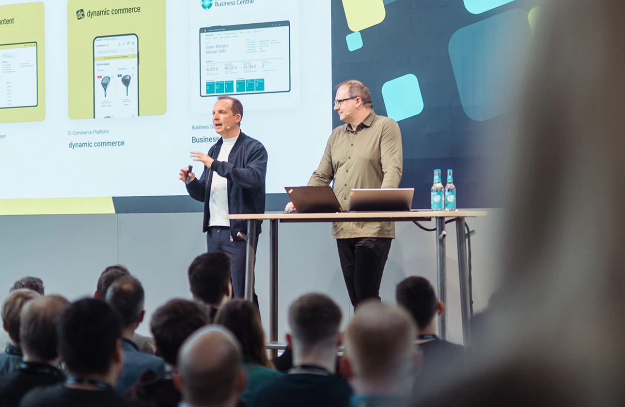 Zwei Experten halten einen Fachvortrag über Digitalberatung und Dynamic Commerce auf einer Bühne vor Publikum.