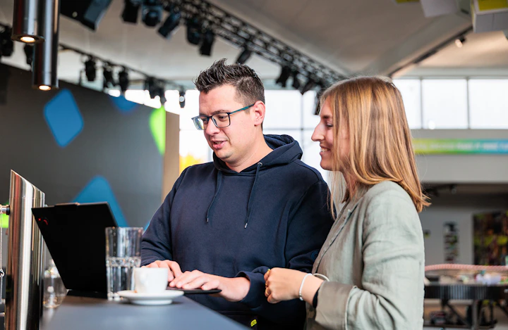 Zwei Kollegen besprechen ein Projekt an einem Lenovo ThinkPad Laptop.