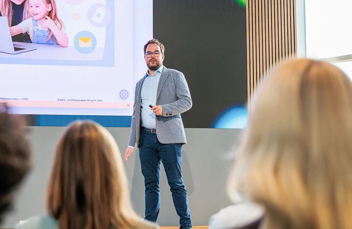 Ein Berater hält einen Vortrag zur Digitalberatung vor Publikum in einem Konferenzraum.