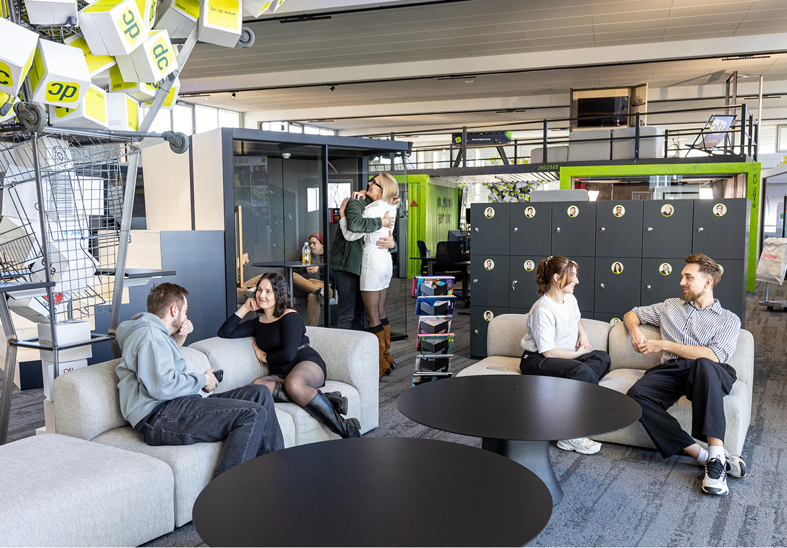 Mitarbeiter unterhalten und umarmen sich im modernen dc-Großraumbüro mit Lounge-Möbeln.